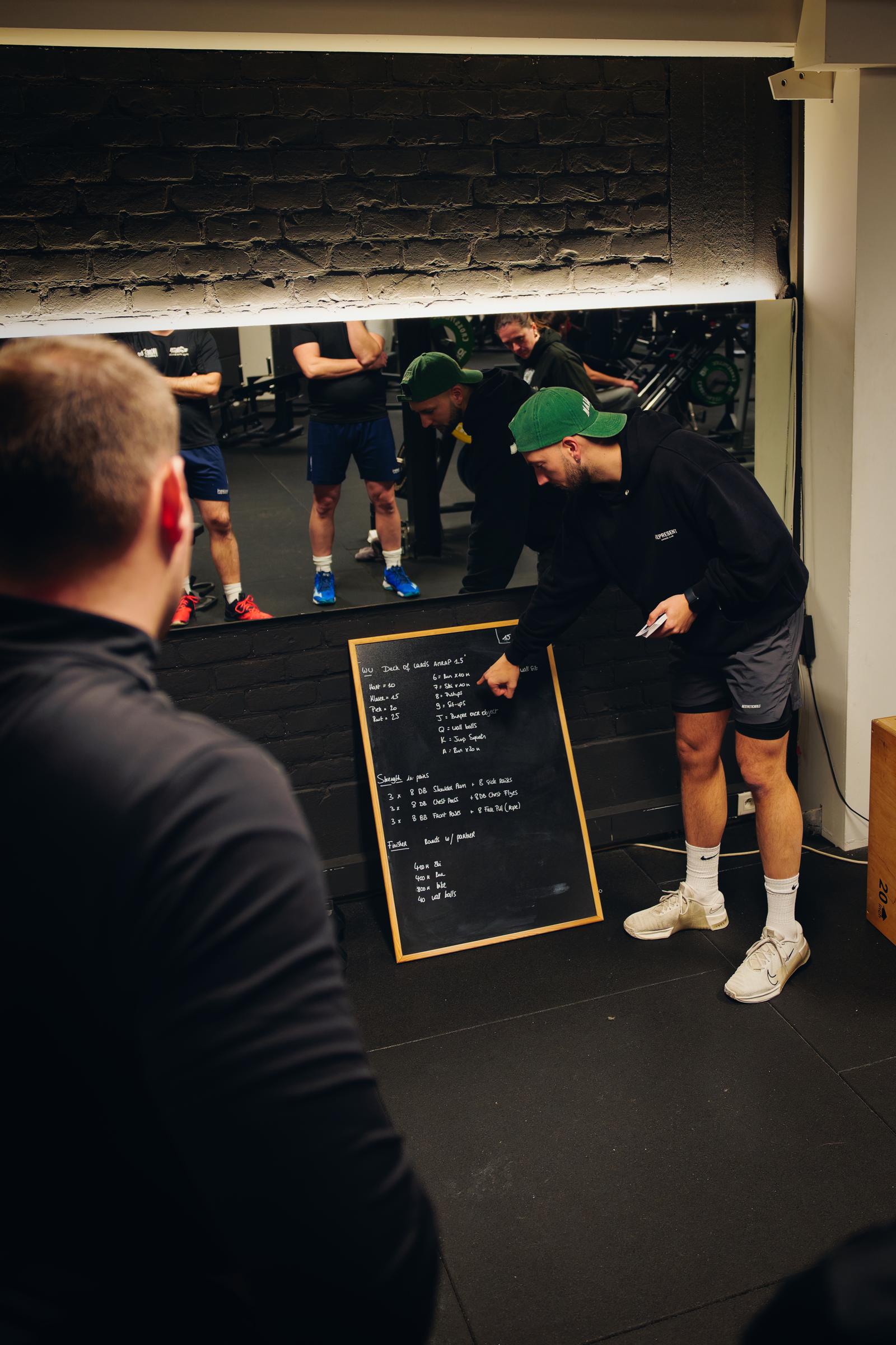 Loïc explaining the session plan on a chalkboard to a small group
